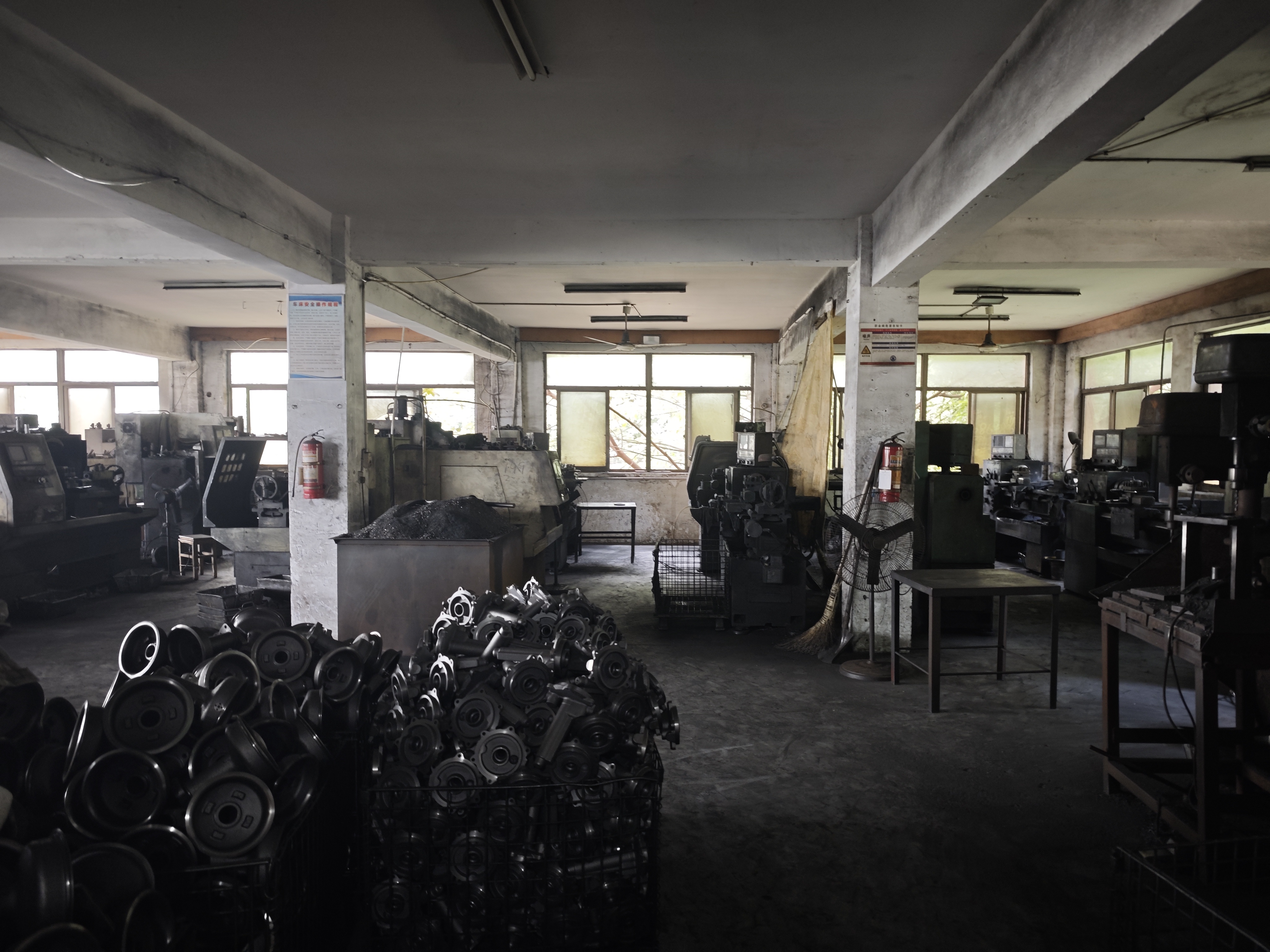 Workshop floor with machining equipment and baskets of metal parts